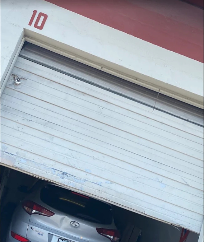 EJ'S Auto Solutions, unit 10, roll-up door part way open with a car inside