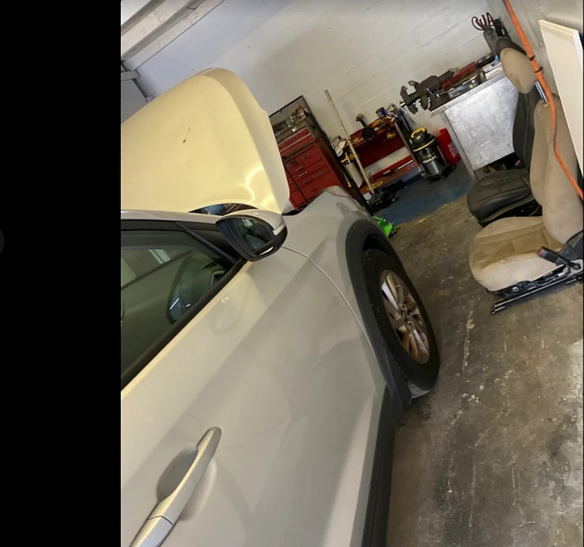 Inside the bay: a car with the hood up beside a red tool chest