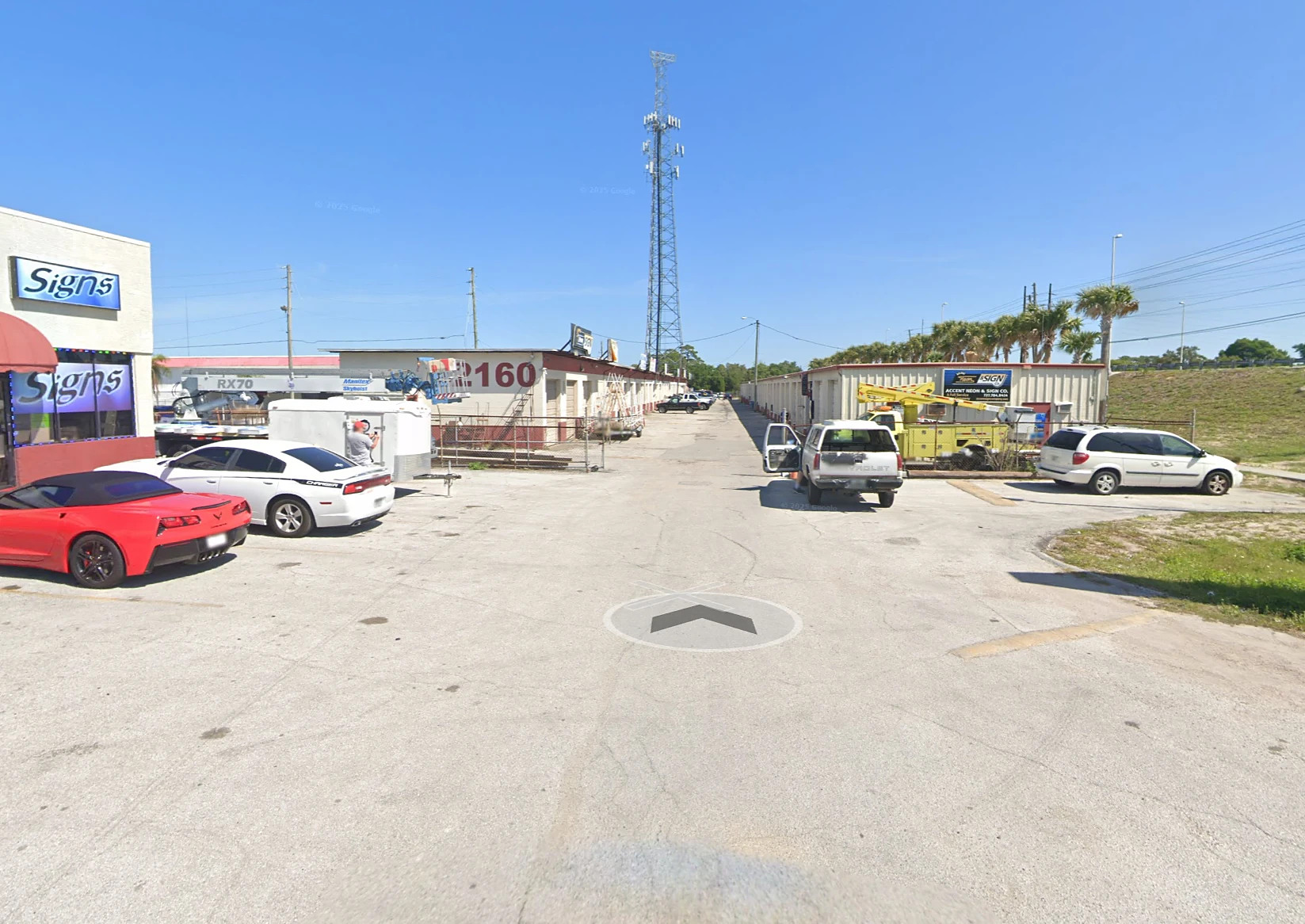 Inside the lot: 2160 painted on the end wall, a sign shop on the left, the cell tower above, and the aisle running straight ahead